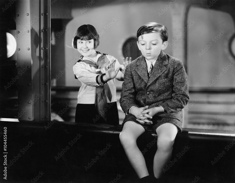 Girl behind a boy pretending to push him overboard Stock Photo