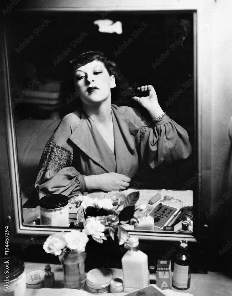 Woman sitting in front of her vanity looking into the mirror Woman sitting in front of her vanity looking into the mirror