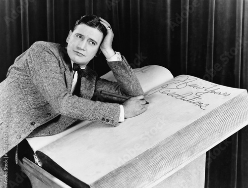 Young man writing into an oversized note book 