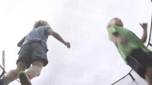 Three kids jumping on a trampoline, angle from underneith. photo