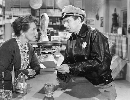 Policeman standing in at a counter in a general store  photo