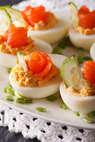 Beautiful food: Eggs stuffed with salmon and cucumber closeup. vertical
