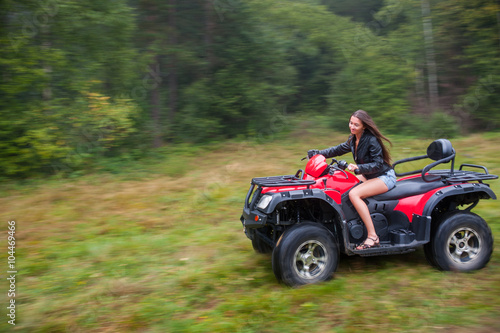 Beautiful girl driving four-wheeler ATV. Motion picture