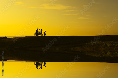 silhoutte of a man standing with his bike during beautiful golden sunrise