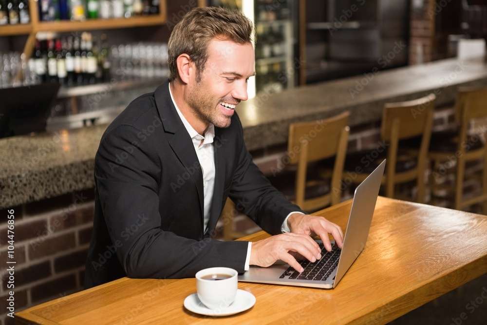 Handsome man using laptop and having a coffee