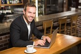 Handsome man using laptop and having a coffee
