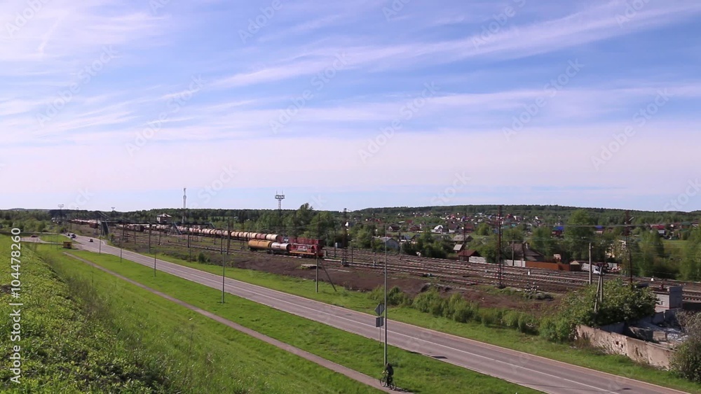 Railway train with two tanks moves next to road and beautiful sky Railway train with two tanks moves next to road and beautiful sky
