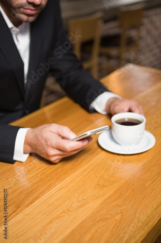 Businessman using smartphone and having coffee