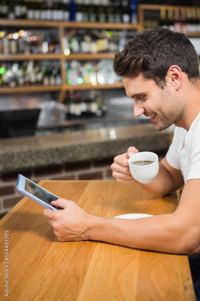 Handsome man using tablet and having coffee Handsome man using tablet and having coffee
