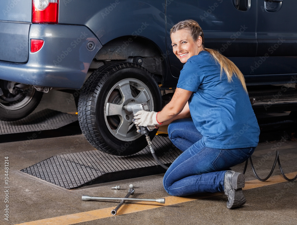 Happy Female Mechanic Fixing Tire With Pneumatic Wrench Happy Female Mechanic Fixing Tire With Pneumatic Wrench