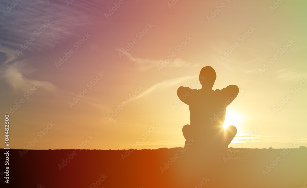 young man doing yoga at sunset sky