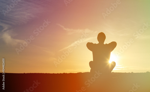 young man doing yoga at sunset sky
