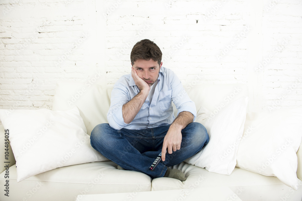 bored man watching television sitting on sofa holding remote control tired not having fun bored man watching television sitting on sofa holding remote control tired not having fun