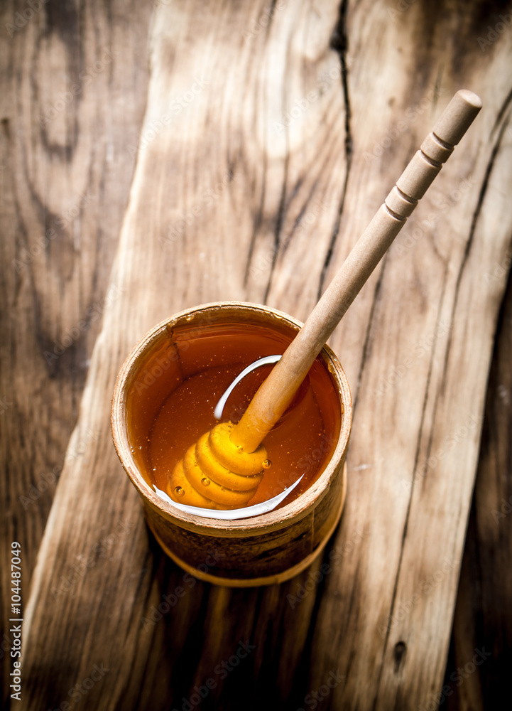 Natural honey in wooden barrel with spoon. Natural honey in wooden barrel with spoon.