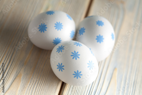 Three white Easter eggs on wooden board