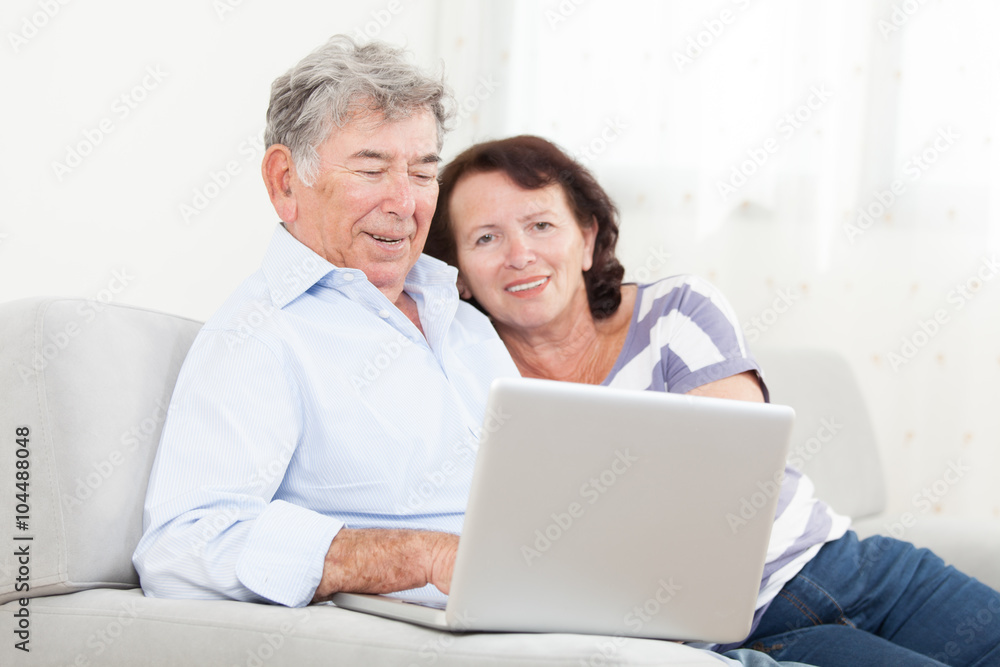 Senior couple laughing while using laptop