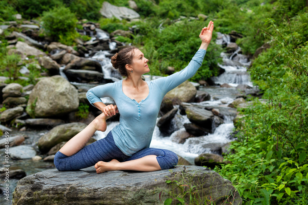 Woman doing yoga asana at tropical waterfall Woman doing yoga asana at tropical waterfall