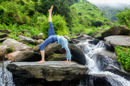 Woman doing yoga asana at waterfall