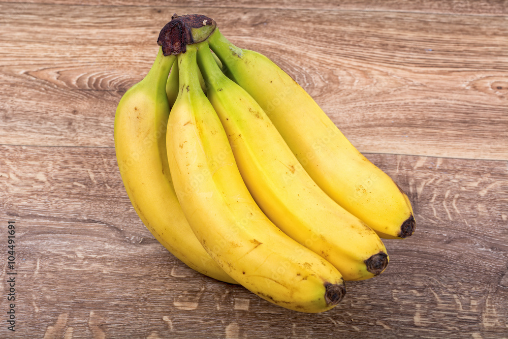A clump of yellow bananas on a wooden background A clump of yellow bananas on a wooden background