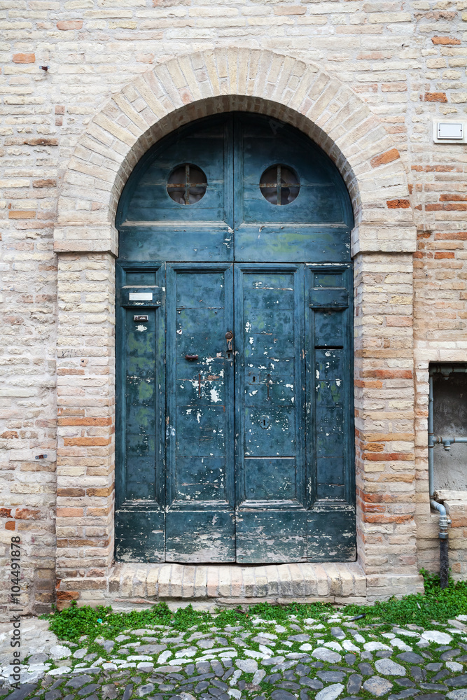 Blue wooden door with arch in old stone wall Blue wooden door with arch in old stone wall