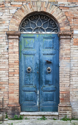 Blue wooden door with arch in old brick wall © evannovostro
