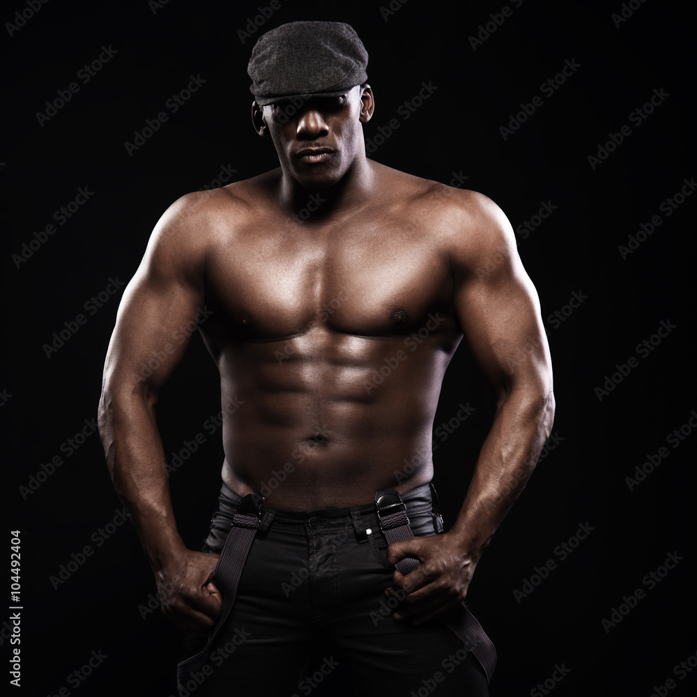 Portrait of an athletic african american man topless. Only in suspenders and cap