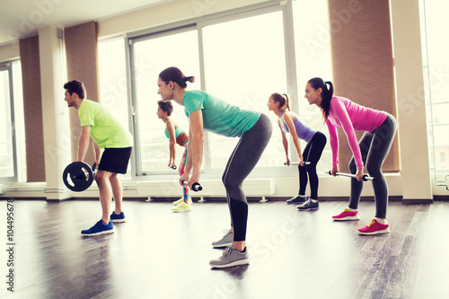 group of people exercising with barbell in gym