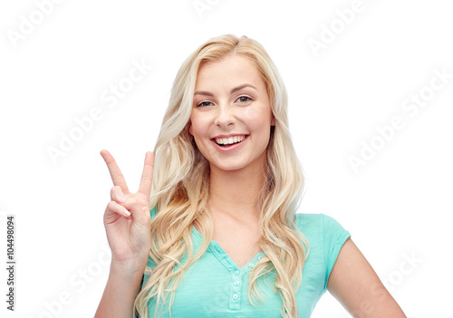smiling young woman or teenage girl showing peace