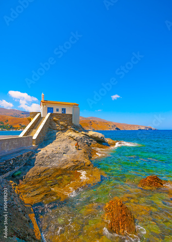 Unidentified man fishing on the rocks at Andros island in Greece