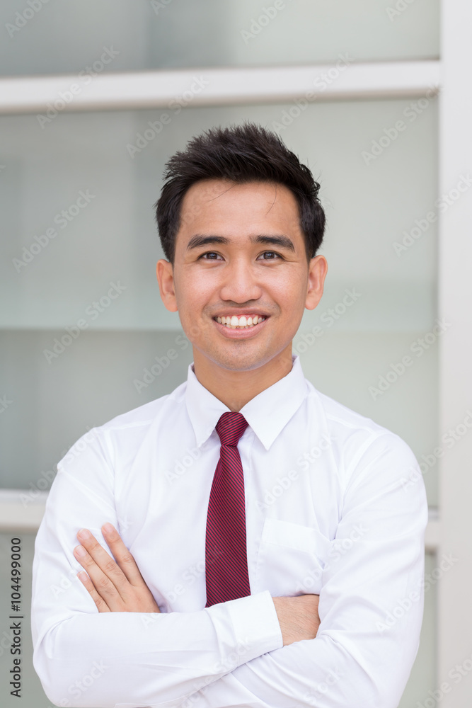 Asian businessman standing arms crossed and smiling Asian businessman standing arms crossed and smiling