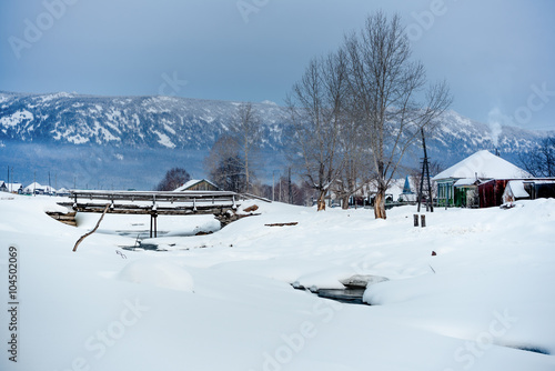 Early morning in a mountain village in Russia.Frozen river in winter wonderland