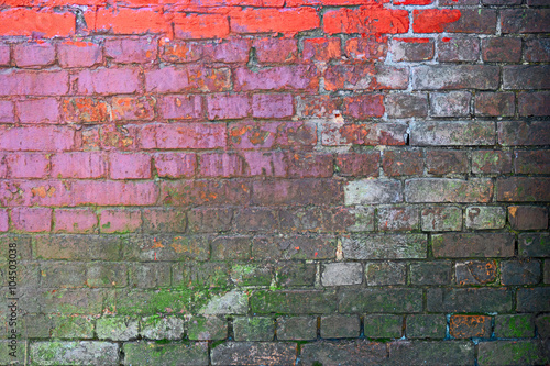 Weathered brick wall painted in pink and green color © mettus