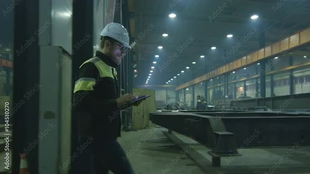 Engineer in hardhat is moving through a heavy industry factory with a tablet computer. Shot on RED Cinema Camera. Engineer in hardhat is moving through a heavy industry factory with a tablet computer. Shot on RED Cinema Camera.