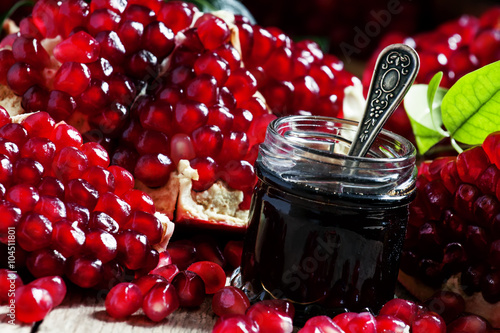 Homemade pomegranate jam in a glass jar with a spoon, fresh open photo