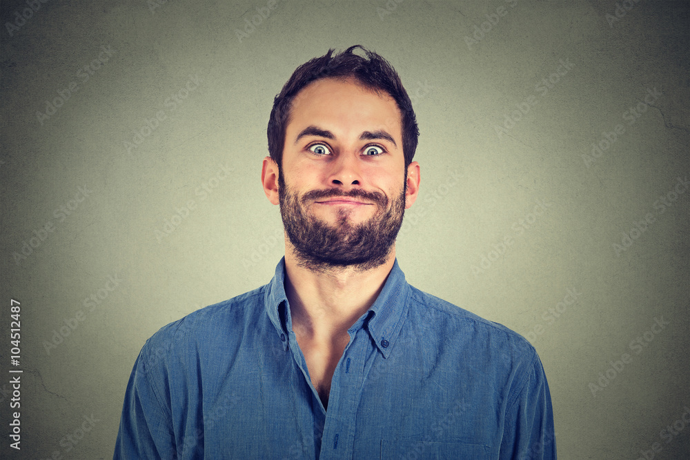 Crazy looking man making funny faces isolated on gray wall background .  Stock Photo | Adobe Stock