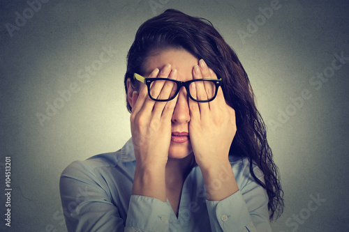 portrait young woman in glasses covering face eyes using her both hands photo