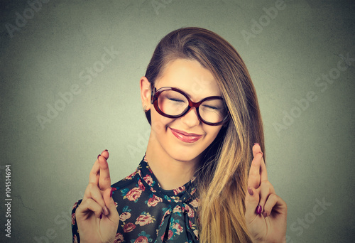 hopeful beautiful woman crossing her fingers, eyes closed, hoping, asking best