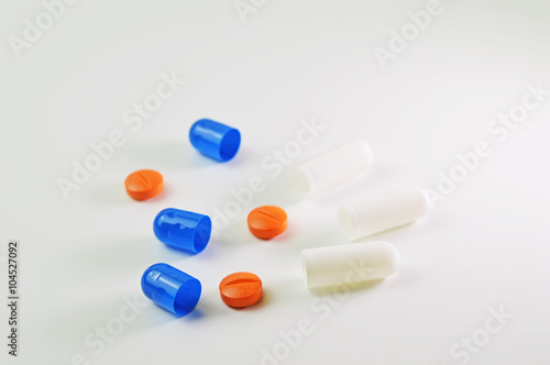 Blue and white capsules and orange tablets