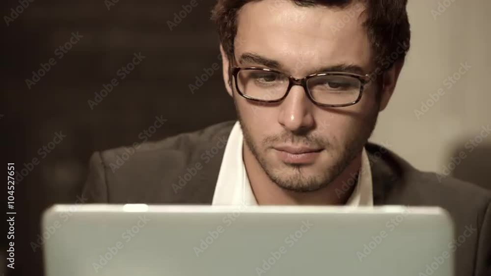 A young businessman working on his laptop in cowerking office A young businessman working on his laptop in cowerking office