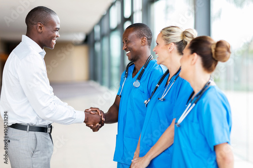 medical rep handshaking with group of doctors