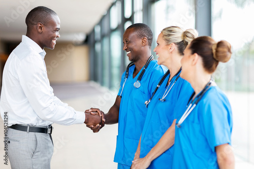 medical rep handshaking with group of doctors