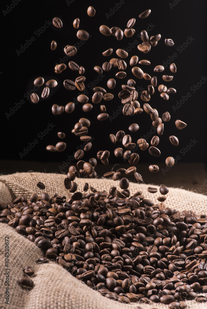 Obraz premium cascata di chicchi di caffè in sacco di iuta