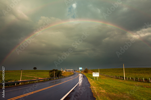 Rainbow after a storm in a wet highway