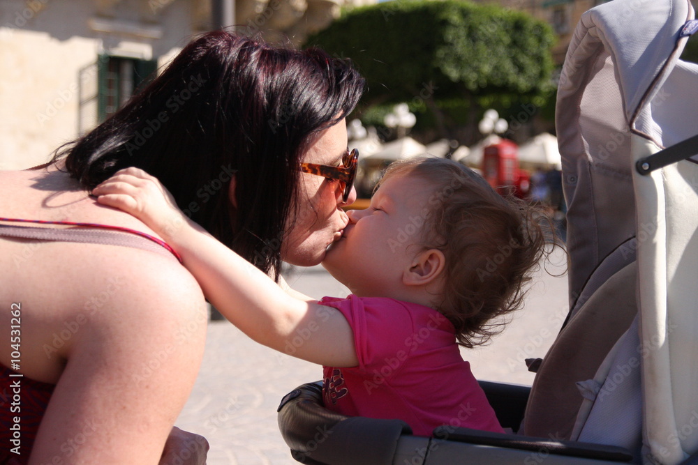 A beautiful little girl kisses her mommy