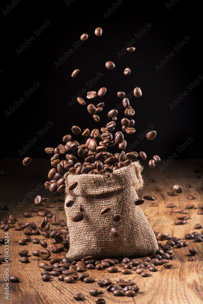 Obraz premium cascata di chicchi di caffè in sacco di iuta