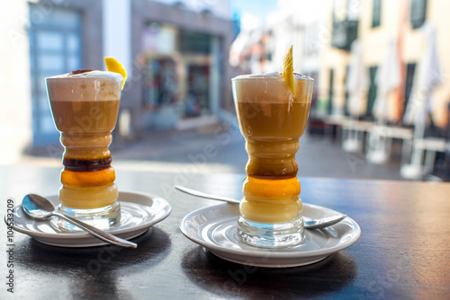 Traditioanl canarian coffee barraquito on the table with city on background photo