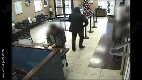 Surveillance camera footage of an armed robber robbing a bank.
