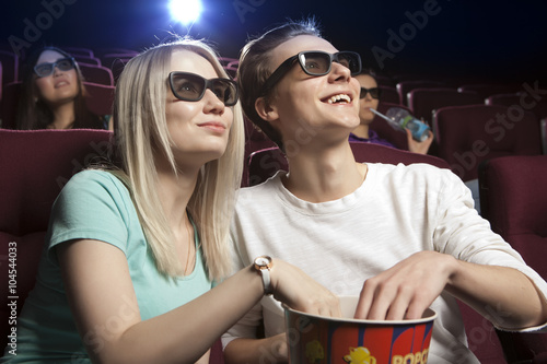 Young couple sitting at the cinema, watching a film