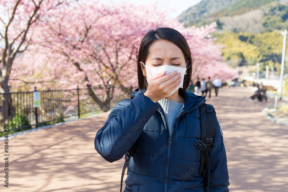 Woman feeling unwell with Pollen allergy under sakura tree Woman feeling unwell with Pollen allergy under sakura tree