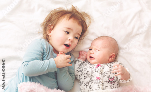 Toddler girl playing with her newborn sister